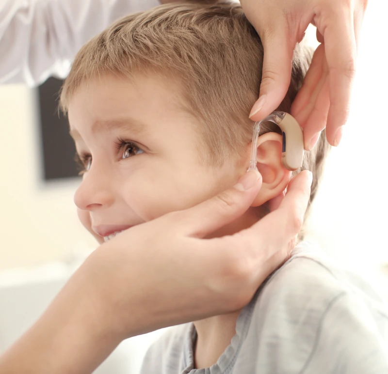 Chłopiec z dysfunkcją słuchu, któremu lekarka zakłada aparat słuchowy